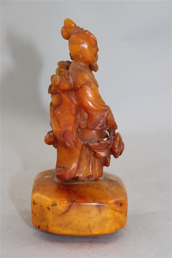 A Chinese egg yolk yellow amber figure of He Xiangu, 20th century, 14cm, glued repairs